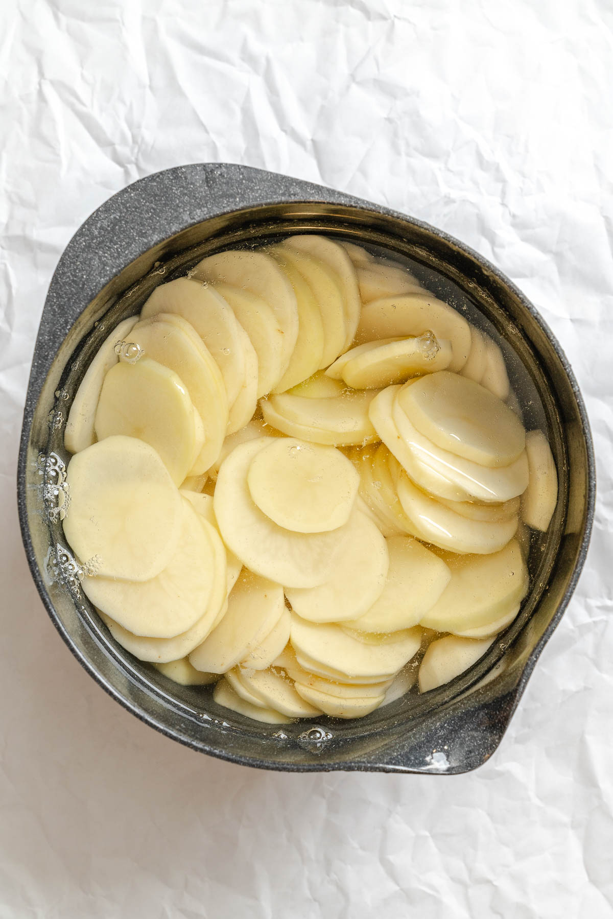 Process shot showing potatoes in a pan.