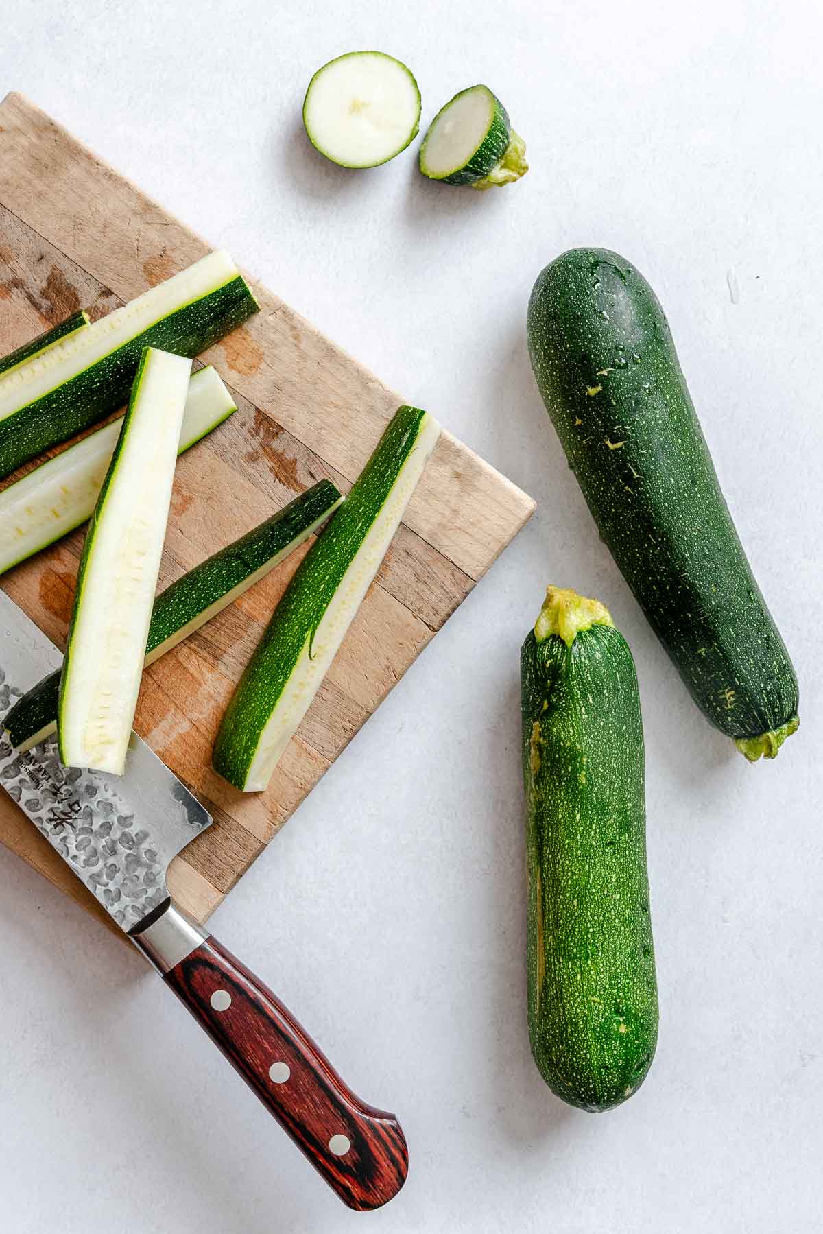 Process shot showing using knife to cut zucchini slices.