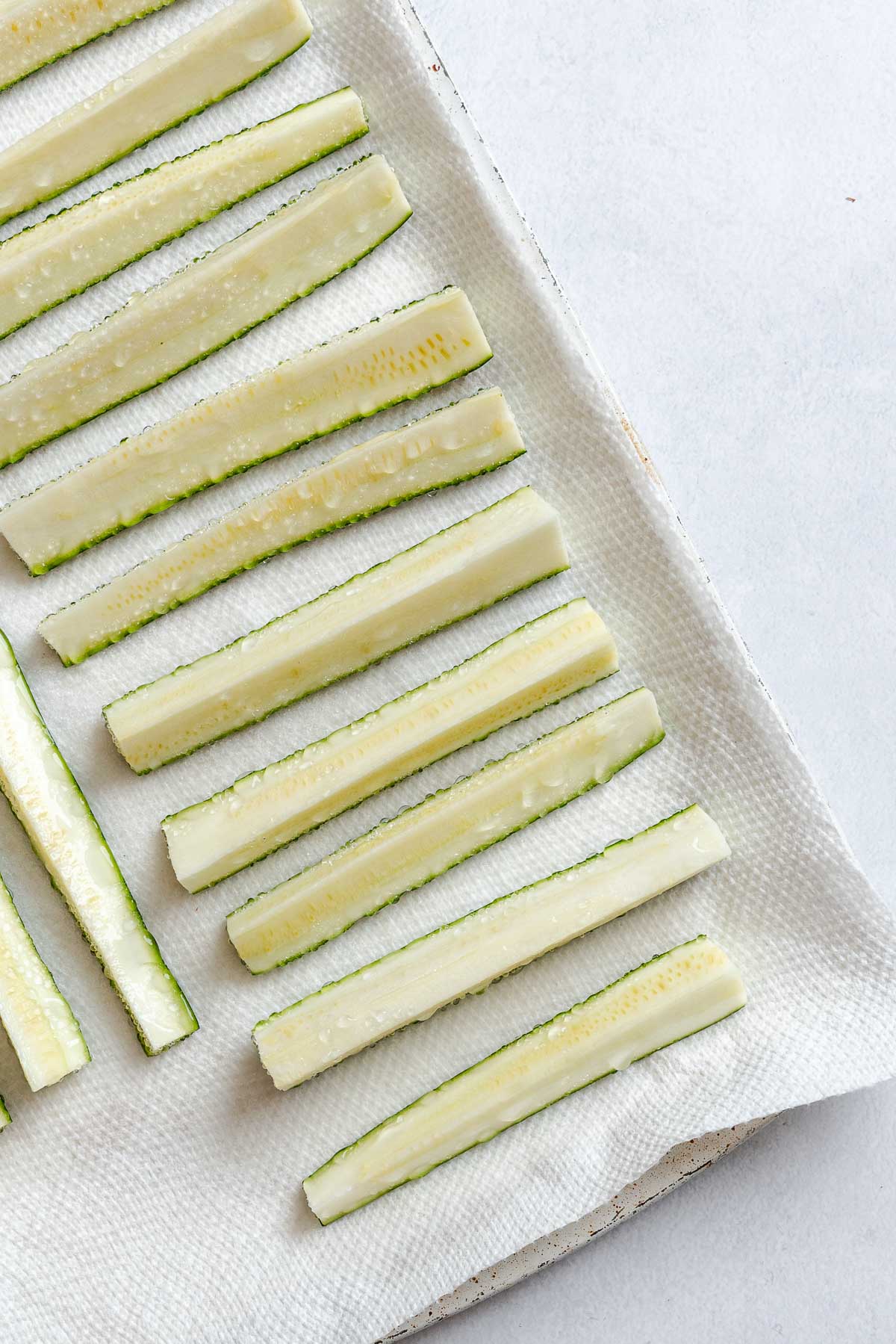 Process shot showing salt added to zucchini slices.