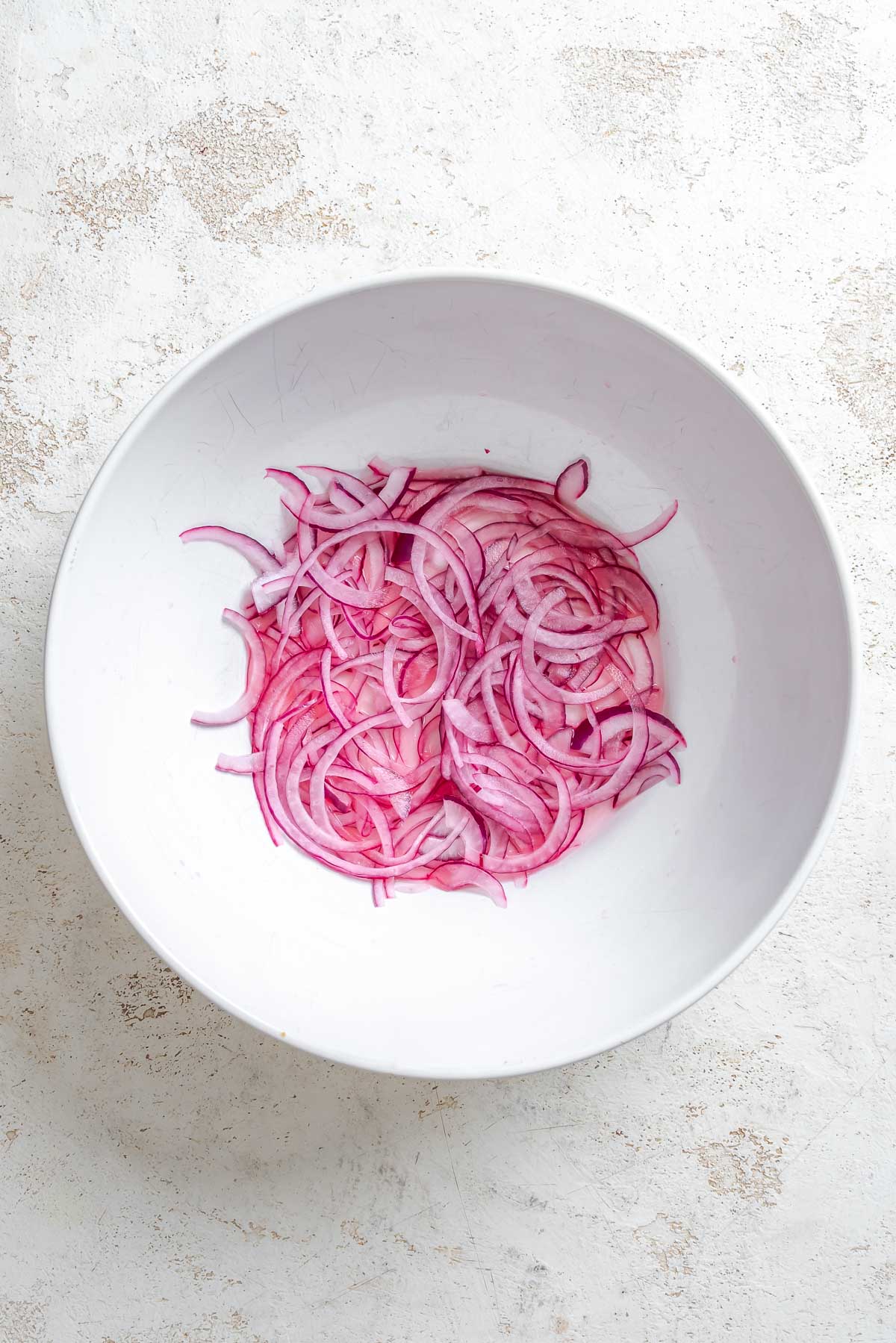 Process shot showing red onions in a bowl.